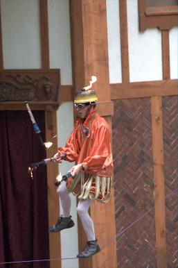 Barto juggling fire on a tightrope supported by five men.