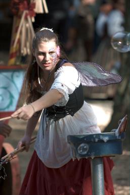 A fairy makes bubbles for the little children.